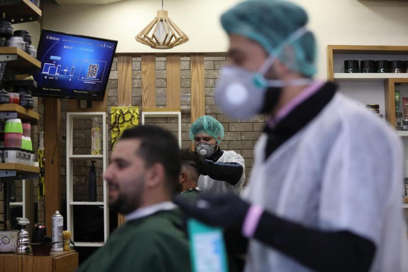 Petugas sebuah barbershop di Kota Nablus Tepi Barat Palestina mengenakan masker dan perlengkapan lain saat mencukur, Ahad (22/3). Pemerintah palestina memerintahkan karantina mandiri selama 14 hari mengantisipasi penyebaran virus corona. Palestina mengkonfirmasn 58 kasus  positif Corona di wilayahnya.  