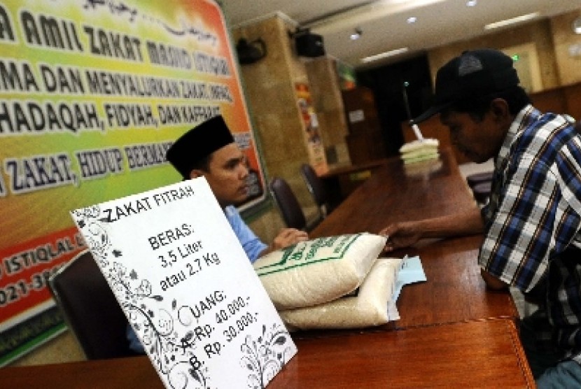 Petugas sedang berbicara dengan warga di tempat penerimaan zakat di Masjid Istiqlal, Jakarta.