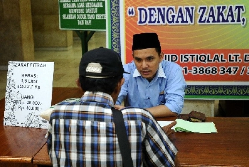 Petugas sedang berbicara dengan warga pada tempat penerimaan zakat di masjid Istiqlal, Rabu (16/7).