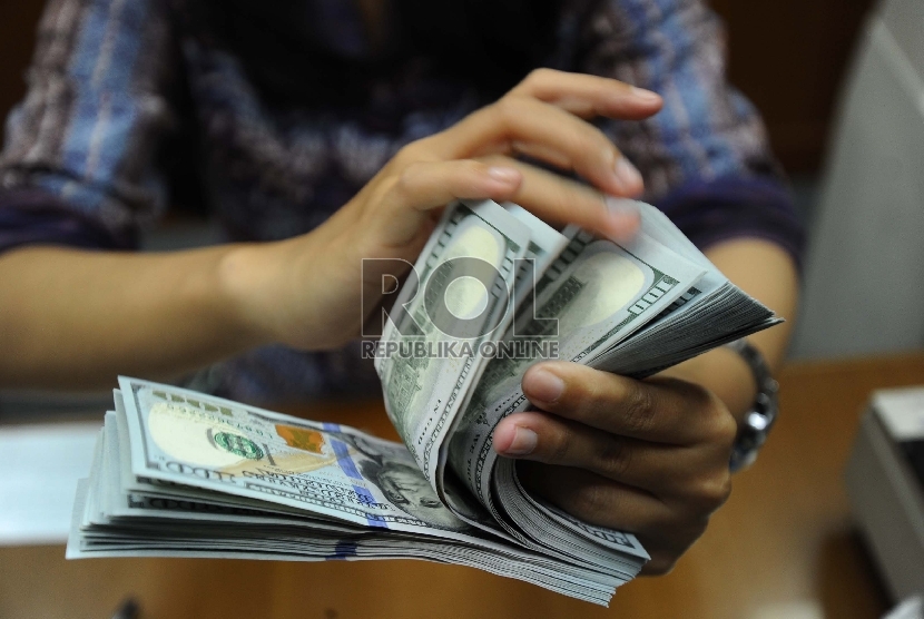 Petugas sedang menghitung uang di money changer (Ilustrasi). Seorang pria yang berdomisili di Banten menjadi tersangka penukaran cek expired di money changer. 