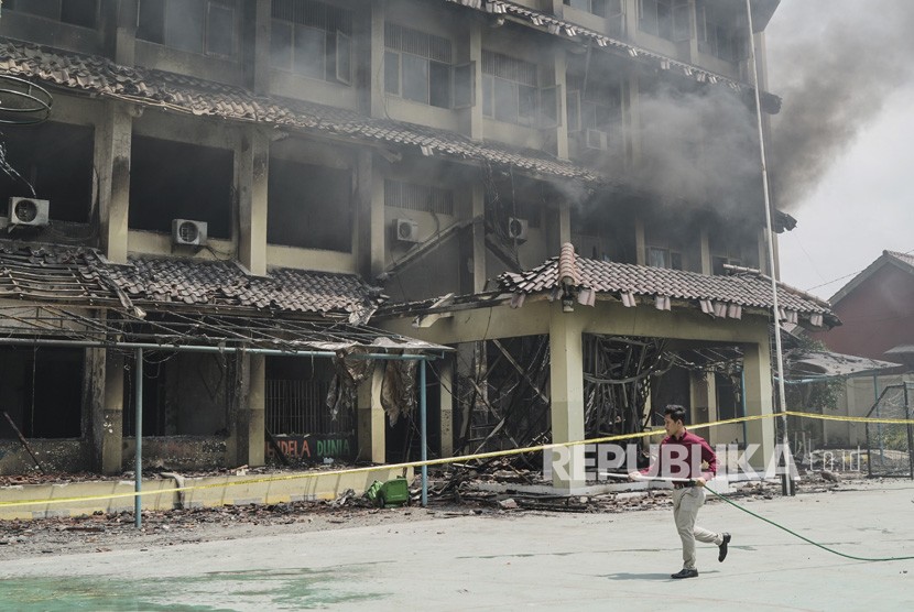 Petugas sekolah berusaha memadamkan api di Lantai 2 SMK (Sekolah Menengah Kejuruan) 6 Yadika (Yayasan Abdi Karya) yang kembali menyala, Bekasi, Jawa Barat, Selasa (19/11/2019).
