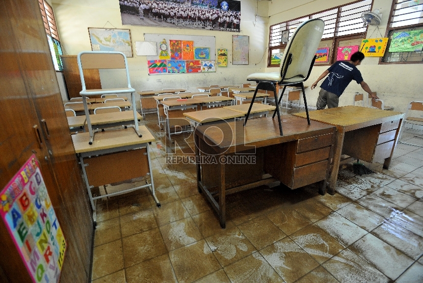 Petugas sekolah membersihkan ruang kelas yang terendam banjir di SD 4 Penjaringan, Jakarta Utara, Selasa (10/2).
