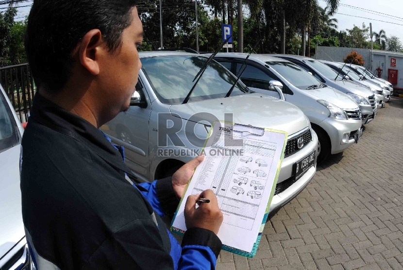 Petugas sewa mobil memeriksa kondisi mobil yang disewakan (ilustrasi)