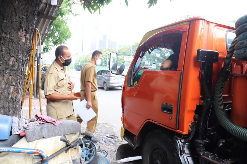 Petugas Suku Dinas Lingkungan Hidup Jakarta Selatan menindak operator truk sedot WC yang tertangkap basah sedang buang limbah tinja di saluran air warga di Mampang Prapatan.