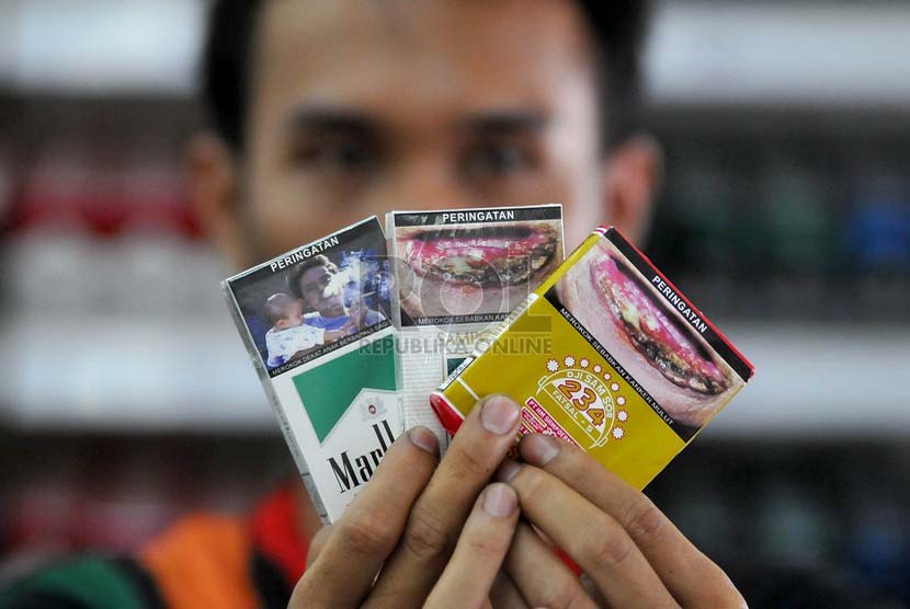 Petugas supermarket menunjukan sejumlah rokok yang sudah dilengkapi peringatan bergambar akan bahaya merokok di Jakarta, Senin (23/6).