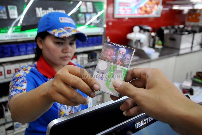 Petugas supermarket menunjukan sejumlah rokok yang sudah dilengkapi peringatan bergambar akan bahaya merokok di Jakarta, Senin (23/6).