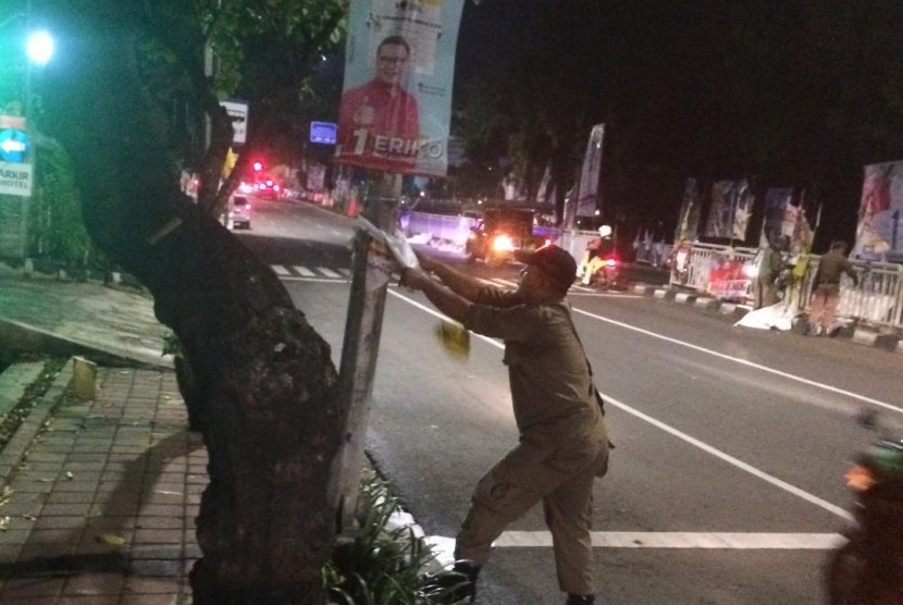 Petugas Tamtib DKI membersihkan atribut kampanye di kawasan Pancoran, Jakarta Selatan, Ahad dinihari, (14/1).