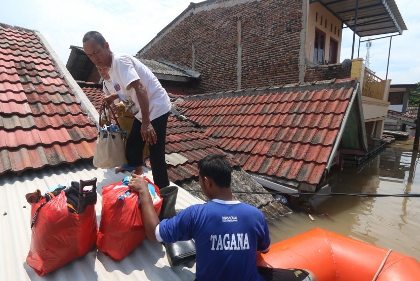 Petugas Taruna Siaga Bencana (TAGANA) Kota Tangerang membantu mengevakuasi warga korban banjir di perumahan Total Persada, Tangerang, Banten, Senin (14/11).