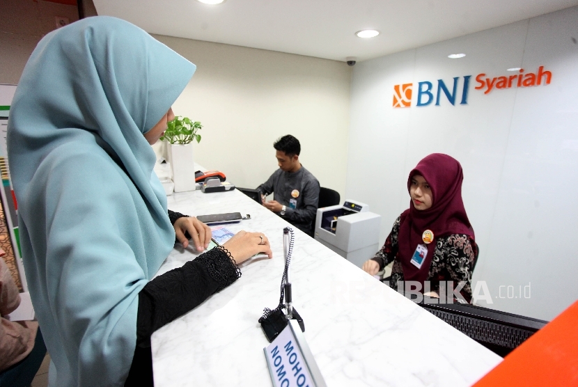 Petugas Teller melayani nasabah di banking Hall BNI Syariah, Jakarta, Jumat (7/7).