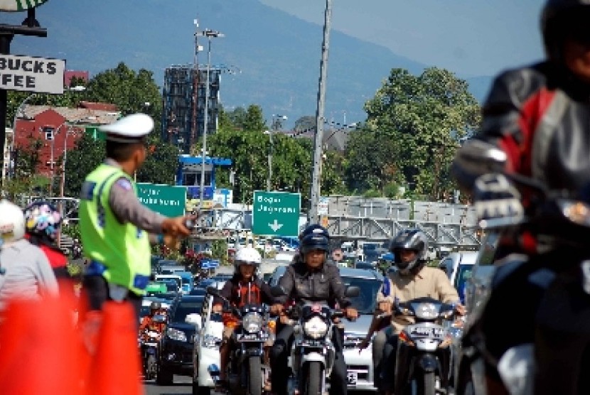 Petugas tengah mengatur arus lalu lintas yang tengah macet.