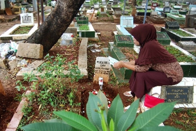 Peziarah berdoa di depan makam sanak saudaranya.