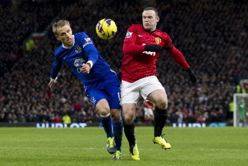 Phil Neville (kiri) berebut bola dengan Wayne Rooney.