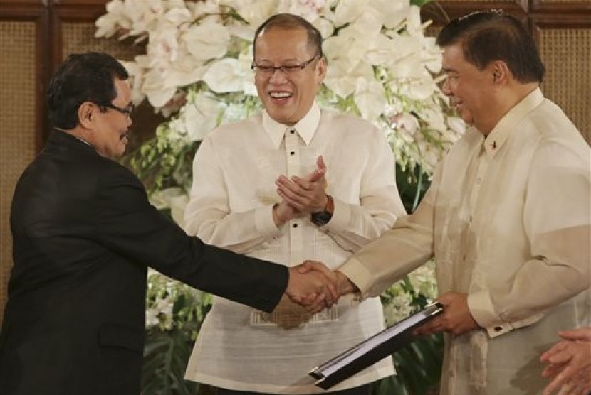 Presiden Filipina Benigno Aquino III (tengah) menyaksikan ketua tim perunding Front Pembebasan Islam Moro (MILF) Mohagher Iqbal (kiri) berjabat tangan dengan Presiden Senat Franklin Drilon di Manila, Filipina.