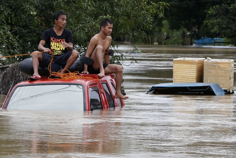 PHILIPPINES - Residents sit on the roof of a vehicle submerged in heavy flooding brought by tropical depression 