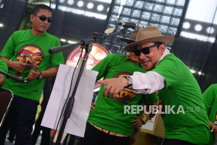 Pimpinan KPK Saut Situmorang (kanan) bernyanyi bersama Grup Orkes Pancaran Sinar Petromaks (PSP) bermain musik dalam aksi kampanye Ngamen Anti Korupsi yang diselenggarakan di Stasiun Gambir, Jakarta, Jumat (13/5).  (Republika/Raisan Al Farisi)