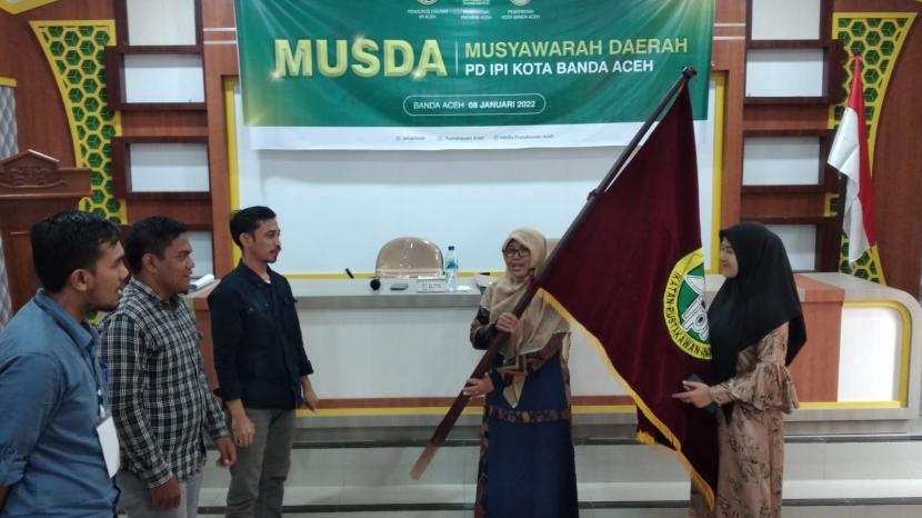   Pimpinan sidang Arkin menyerahkan bendera pataka kepada Yusrawati (tengah) usai terpilih sebagai Ketua PD IPI Kota Banda Aceh, Sabtu (8/1) di Aula FEBI UIN Ar-Raniry Banda Aceh.