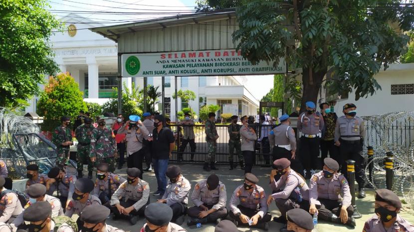 Pintu masuk Pengadilan Negeri Jakarta Timur (PN Jaktim), Jumat (26/3), dijaga ketat aparat TNI-Polri. Di dalam ruang sidang, Habib Rizieq Shibab sedang menjalani sidang pelanggaran protokol kesehatan.