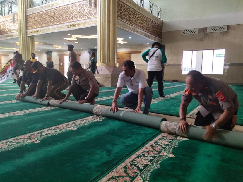 Pengurus masjid menggulung karpet sebagai langkah antisipasi penyebaran virus korona.