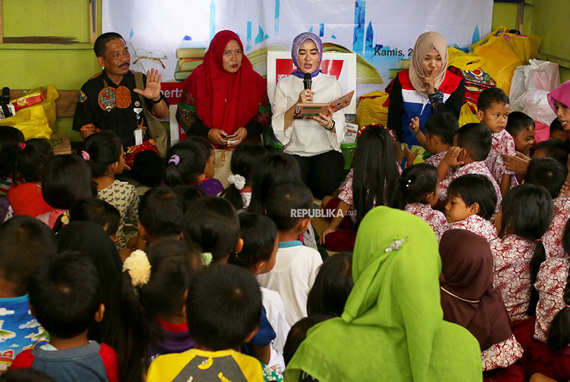 Plt Direktur Utama Pertamina Nicke Widyawati (kedua kanan) membacakan dongeng untuk anak-anak di Rumah Baca Banyu Ilmi, Kampung Baru, Balikpapan, Kalimantan Timur, Kamis (26/4).