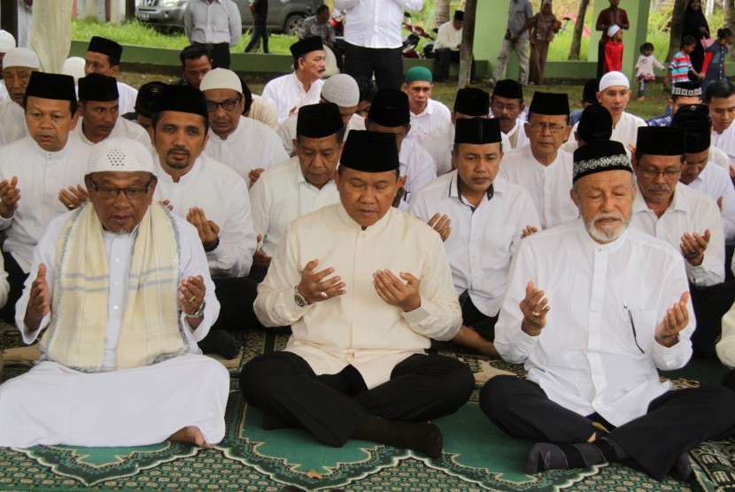 Plt Gubernur Aceh, Soedarmo (tengah) bersama Wali Nanggroe Aceh, Malik Mahmud (kanan) dan pejabat muspida Aceh, berdoa saat ziarah di kuburan massal korban tsunami Aceh di Desa Ulee Lheue, Banda Aceh, Senin (26/12).