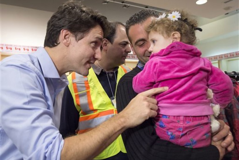 PM Kanada Justin Trudeau (kiri) menyapa pengungsi Suriah, Madeleine Jamkossian (kanan) dan ayahnya Kevork Jamkossian saat tiba di Bandara Internasional Pearson di Toronto, Jumat (11/12).  