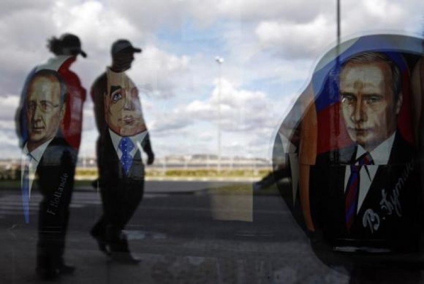 Police are reflected in the window of a shop displaying traditional nesting dolls with images of Russian President Vladimir Putin (right), Prime Minister Dmitry Medvedev (center) and French President Francois Hollande at the sea port in St. Petersburg Sept