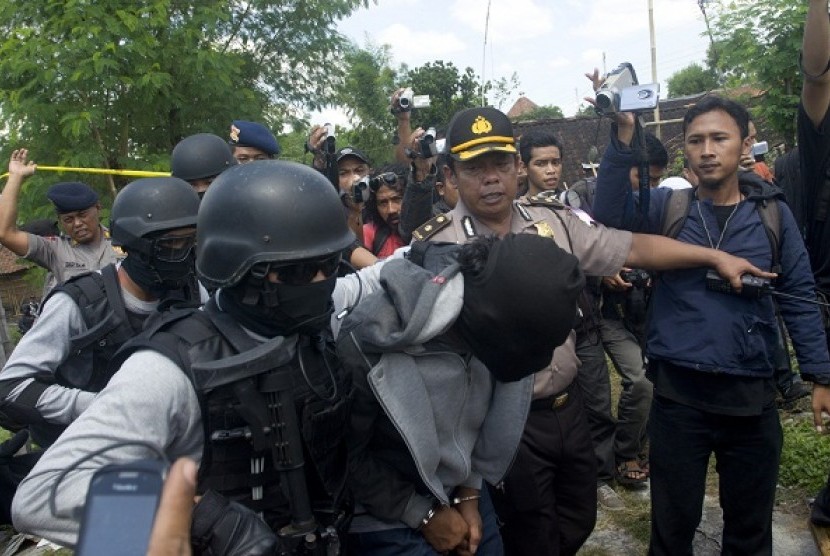 Police holds a suspected terrorist (center) after raid in Solo, Central Java, on Thursday.