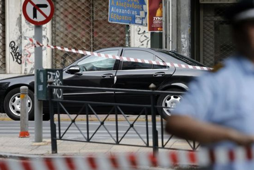 Police memasang garis polisi di lokasi ledakan bom dalam mobil yang ditumpangi mantan PM Yunani  Lucas Papademos di persimpangan kawasan Patission dan Marnis Street, Athena, Yunani.