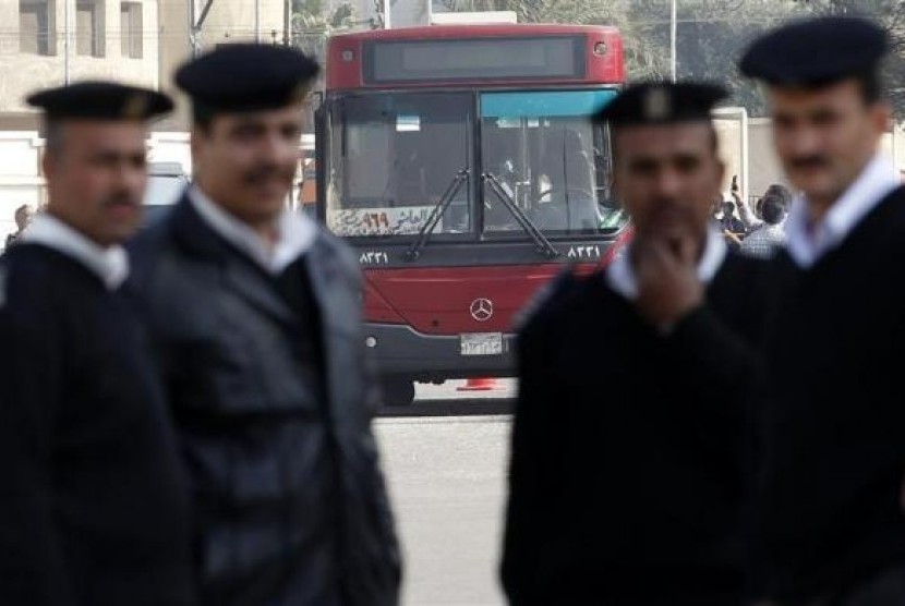 Police officers stand guard in front of a damaged bus after a bomb blast near the Al-Azhar University campus in Cairo's Nasr City district December 26, 2013. 