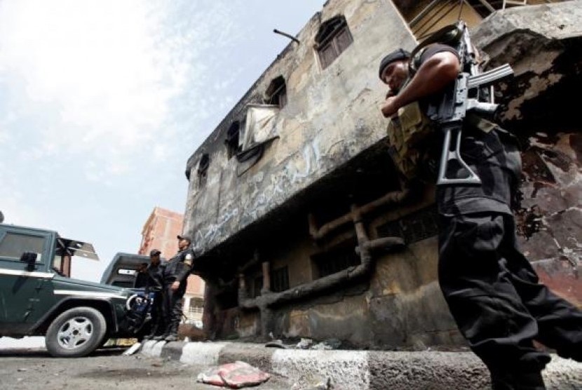 Police officers stand in front of a police station damaged after being set ablaze in August by supporters of former president Mohamed Mursi in Kerdasa, 9 miles from Cairo September 19, 2013.