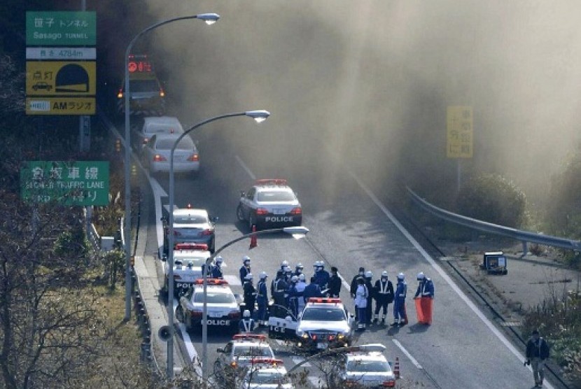 Police vehicles are parked at the entrance as smoke billows out of the Sasago Tunnel on the Chuo Expressway in Koshu, Yamanashi Prefecture, central Japan, Sunday morning, Dec. 2, 2012. A part of the tunnel collapsed Sunday morning, possibly involving sever