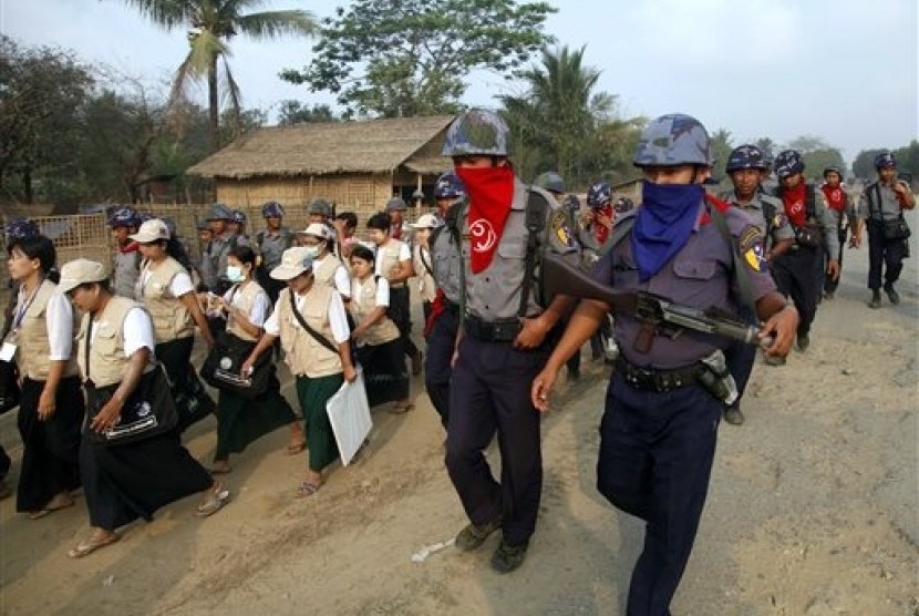 Policemen covers their faces to protect from the dust as they walk with census enumerators at Thae Chaung village in Sittwe, Rakhine State, western Myanmar, Tuesday, April 1, 2014. 