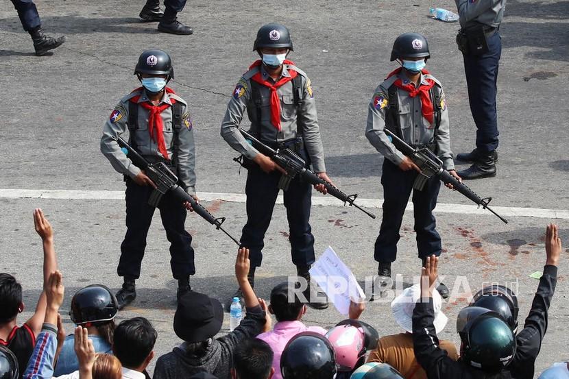  Polisi anti huru hara bersenjata berjaga-jaga saat para demonstran memberi hormat tiga jari, simbol perlawanan, selama protes terhadap kudeta militer di Naypyitaw, Myanmar, Senin (8/2).