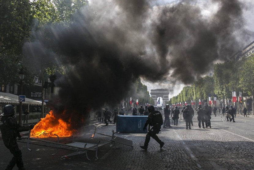 Polisi antihuru-hara Prancis berjaga di Champs-Elysees saat bentrok dengan pengunjuk rasa ketika parade hari Bastille, Ahad (14/7).