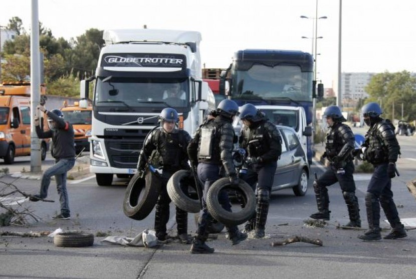 Polisi antihuru-hara Prancis memindahkan ban dan cabang pohon setelah pekerja memblokade jalan dekat kilang minyak Fos-sur-Mer dekat Marseille, Prancis, 24 Mei 2016.