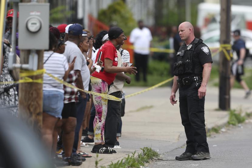 Polisi berbicara dengan para pengamat saat menyelidiki setelah penembakan di sebuah supermarket pada hari Sabtu, 14 Mei 2022, di Buffalo, N.Y.