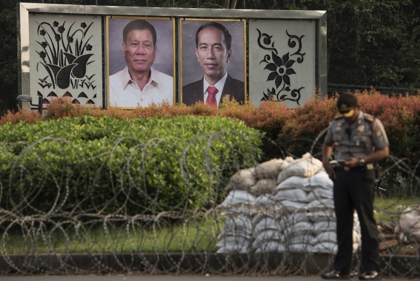 Polisi berdiri di dekat foto Presiden Joko Widodo dan Presiden Filipina Rodrigo Duterte yang dipajang di seberang Istana Merdeka, Jakarta, Kamis (8/9). 