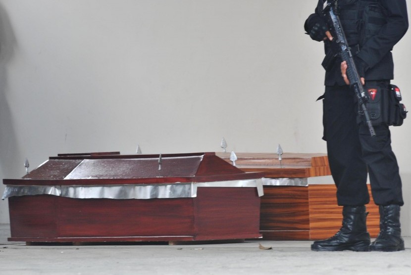 Polisi berjaga di dekat dua peti jenazah di depan Ruangan Instalasi Forensik Rumkit Bayangkara, Palu, Sulawesi Tengah, Selasa (19/7). 