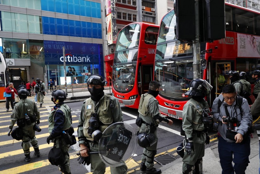 Polisi berjaga di depan halte bus di Hong Kong. PM Li Keqiang menyebut RUU ekstradisi merusak seluruh lapisan masyarakat Hong Kong. Ilustrasi.