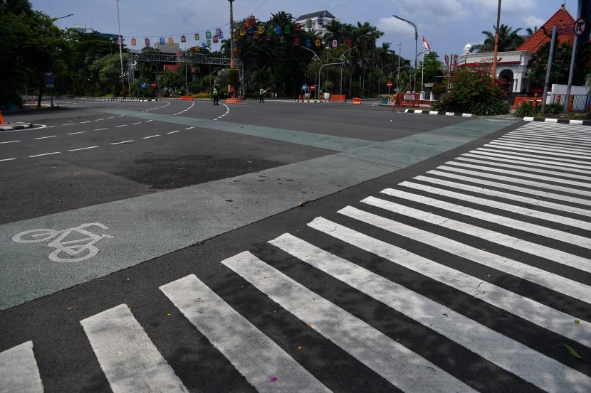 Polisi berjaga di Jalan Darmo yang ditutup, di Surabaya, Jawa Timur, Sabtu (28/3). Penutupan sejumlah jalan di Surabaya tersebut agar terbebas dari segala aktivitas warga dan kendaraan guna mencegah penyebaran Virus Corona (COVID-19).