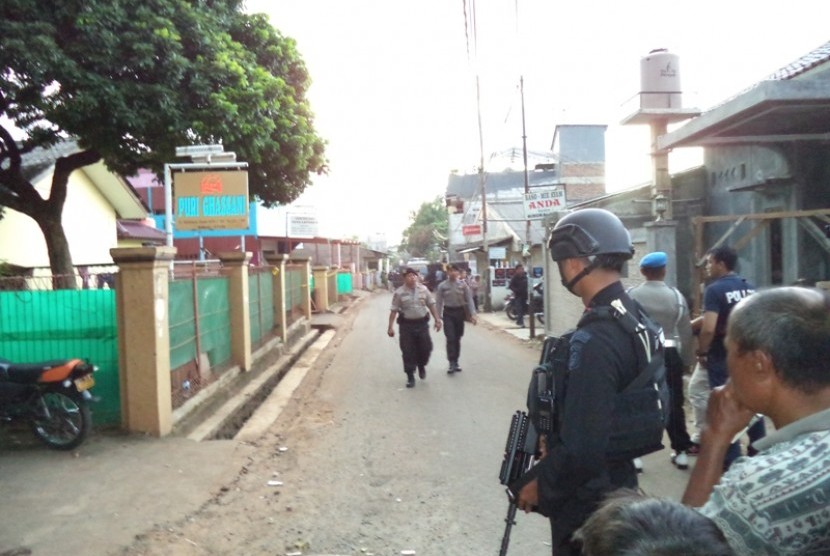 Polisi berjaga di lokasi penggerebakan sebuah rumah di Bintara Jaya, Bekasi, Sabtu (10/12). Di rumah bertingkat tiga bercat biru dan pink ditemukan benda diduga bom.