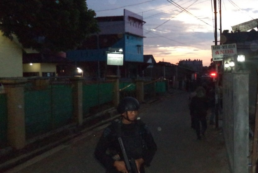 Polisi berjaga di lokasi penggerebakan sebuah rumah di Bintara Jaya, Bekasi, Sabtu (10/12). Di rumah bertingkat tiga bercat biru dan pink ditemukan benda diduga bom.