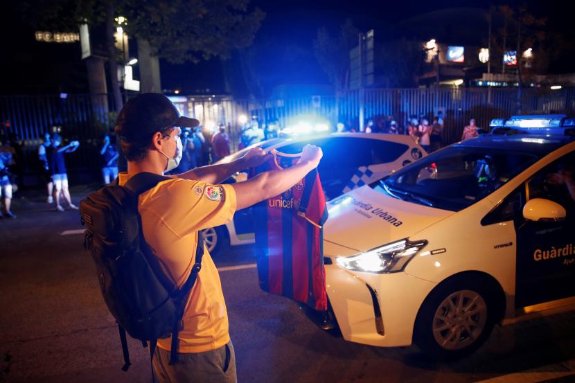 Polisi berjaga di tengah kerumunana massa yang melakukan demonstrasi di depan Stadion Camp Nou, Rabu (26/8). Massa adalah suporter Barcelona yang menunut Messi tetap tinggal di Camp Nou.