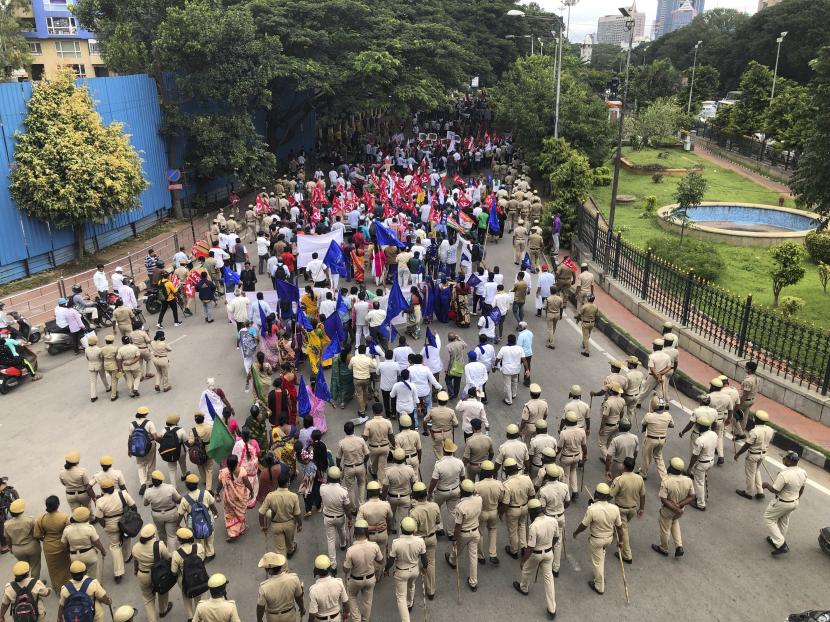 Polisi berjalan bersama para aktivis dari berbagai organisasi berbaris mendukung petani selama penutupan nasional untuk memprotes undang-undang pertanian yang kontroversial di Bengaluru, India, Senin, 27 September 2021