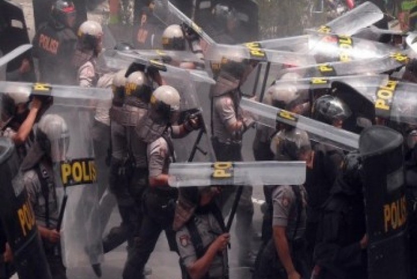 Polisi berlindung dari lemparan masa di depan PN Temanggung saat terjadi kerusuhan pada sidang vonis kasus penistaan agama, Selasa (8/2).