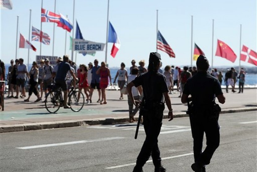 Polisi berpatroli dekat lokasi serangan truk di Promenade des Anglais, Nice, Prancis, Sabtu, 16 Juli 2016. Tampak bendera dikibarkan setengah tiang.