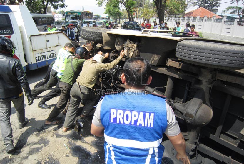 Polisi bersama warga mengevakuasi mobil minibus yang terbalik. (ilustrasi)