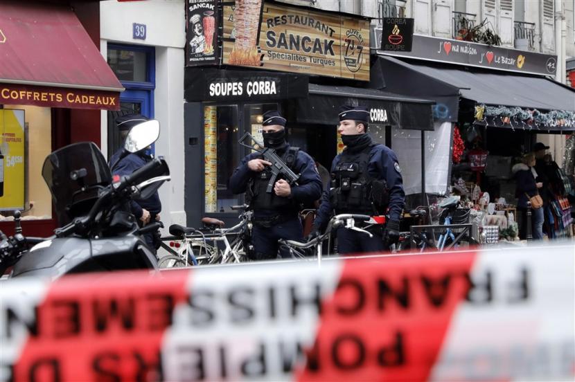 Polisi bersenjata berjaga di sekitar lokasi penembakan di dekat Pusat Kebudayaan Kurdi di Paris, Jumat (23/12/2022).