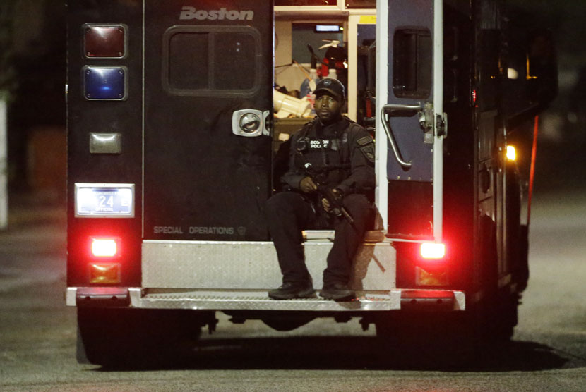  Polisi bersenjata lengkap duduk diatas kendaraan polisi di Watertown, Jumat (19/4).    (AP/Matt Rourke)