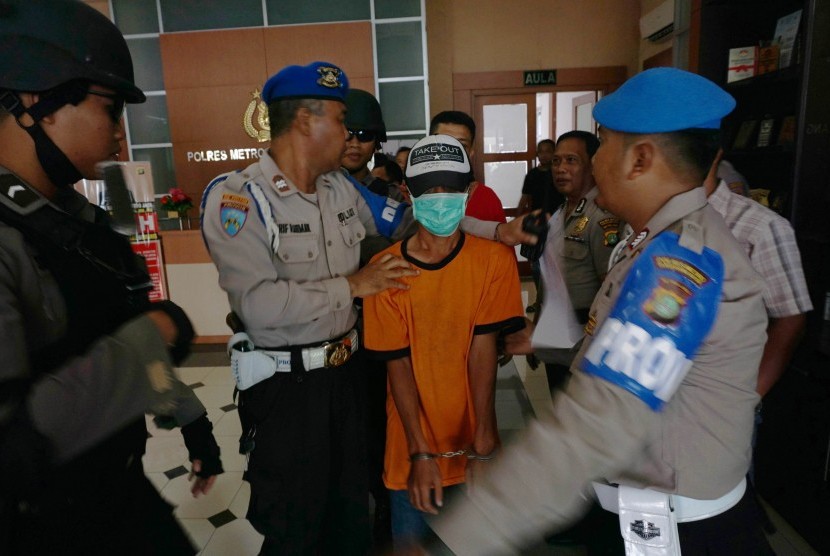 Polisi bersenjata lengkap menjaga pelaku penabrak pengemudi ojek online berinisial SBH (41) saat ungkap kasus di Polres Metro Tangerang, Banten, Jumat (10/3).